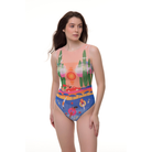 Full-body shot of a model in a Portofino Collection sleeveless one-piece swimsuit, featuring a stylish coastal print with blue and coral hues, standing on a white background.